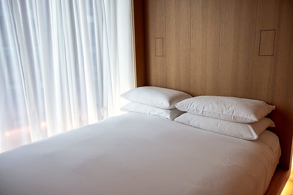 Stacked white linen on a bed with a timber headboard