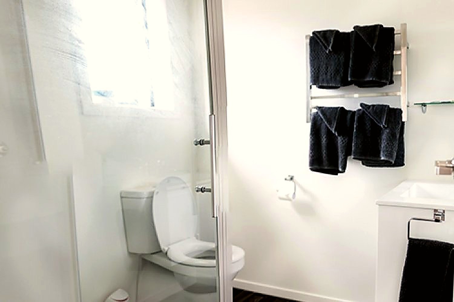 Refurbished bathroom with a shower, toilet and folded towels