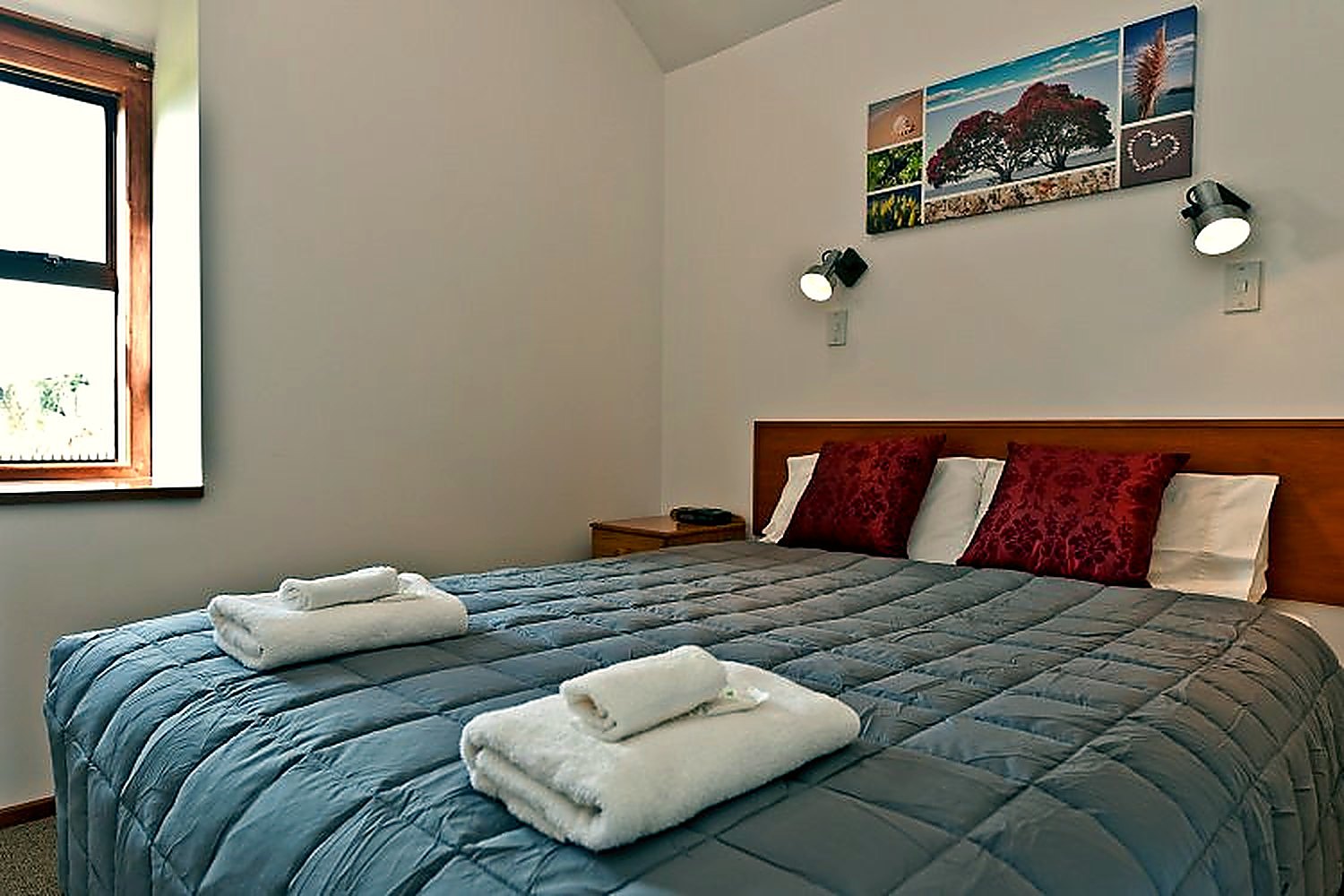 Queen bed made up with fresh towels in a refurbished unit