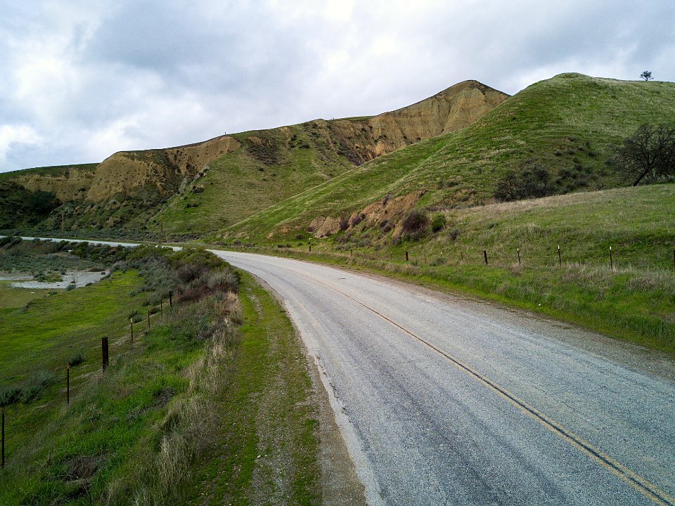 A gravel road climbing through green coastal hills