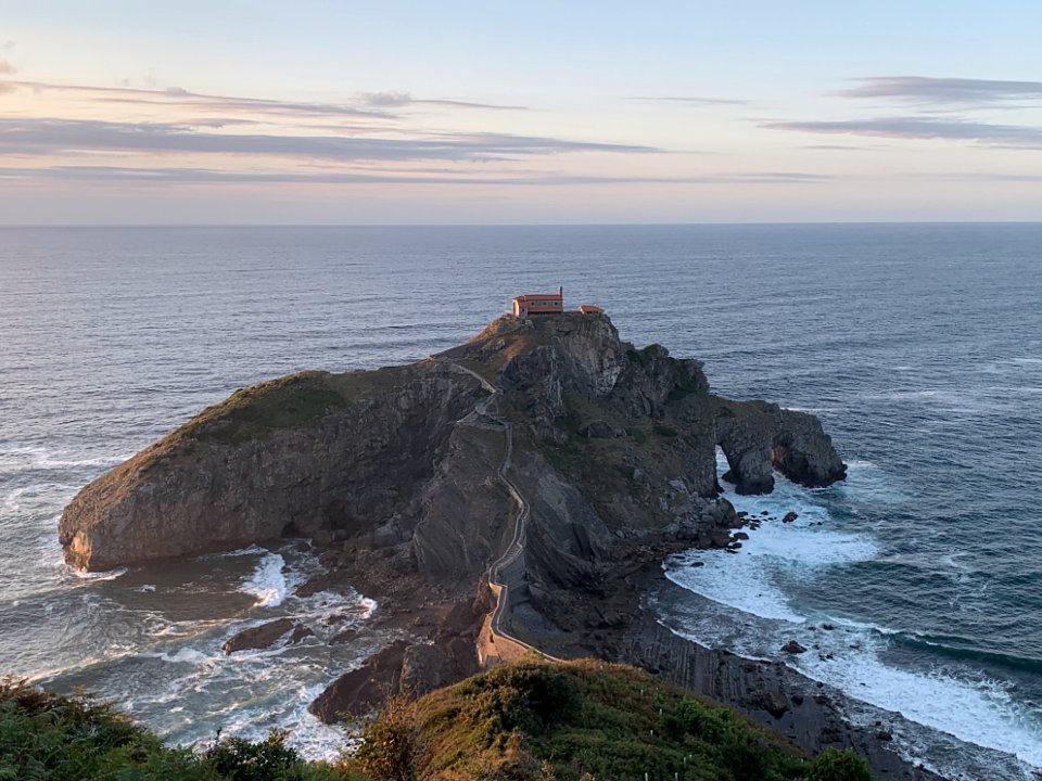 A small island with a lighthouse at sunset