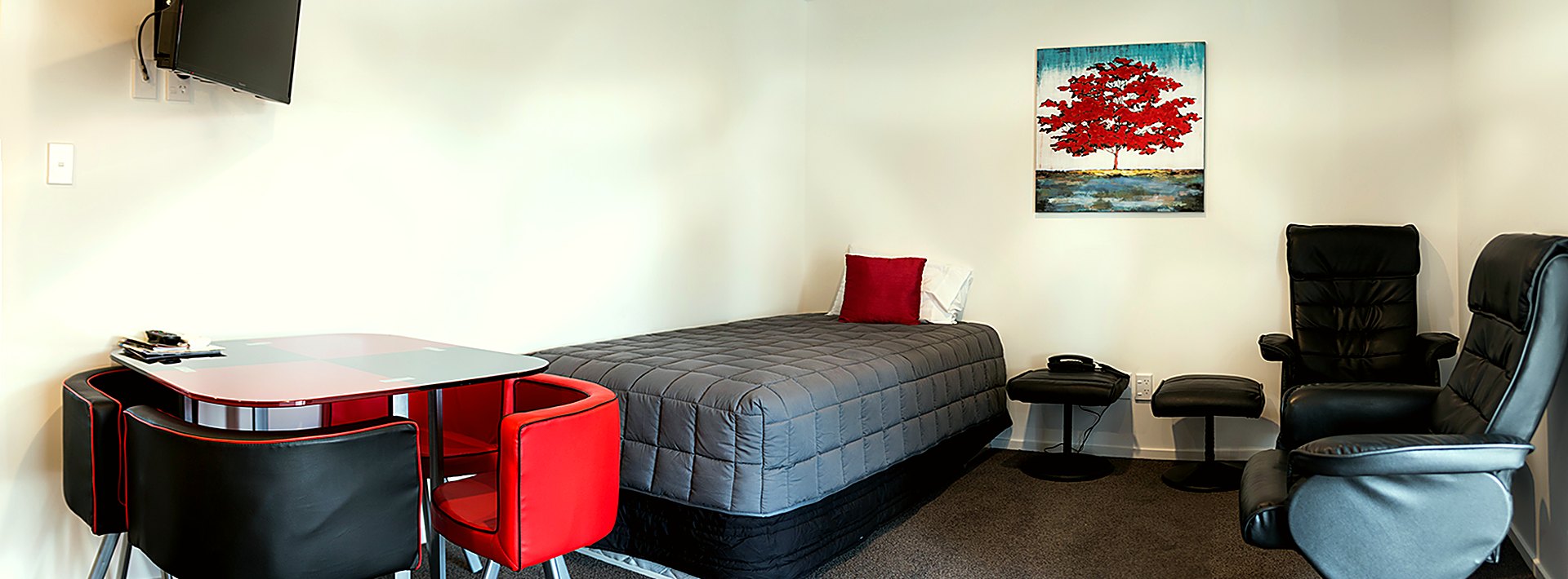 A refurbished Gateway MotorLodge unit with recliner chairs, a dining table and a made bed