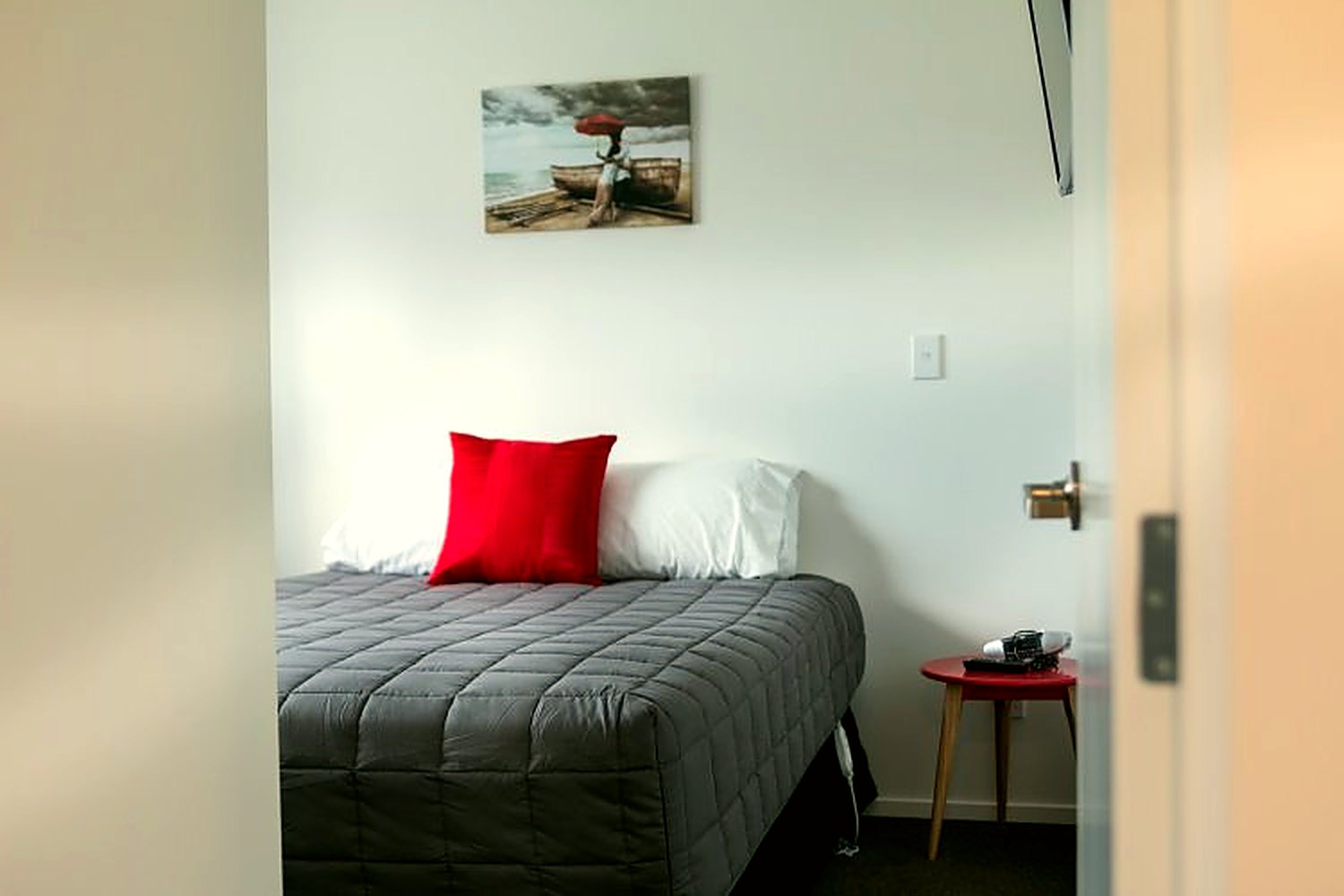 Close view of the studio bed with a red accent cushion